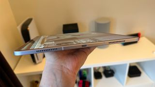 The 13-inch iPad Air being held flat on one hand, showing the bottom edge.